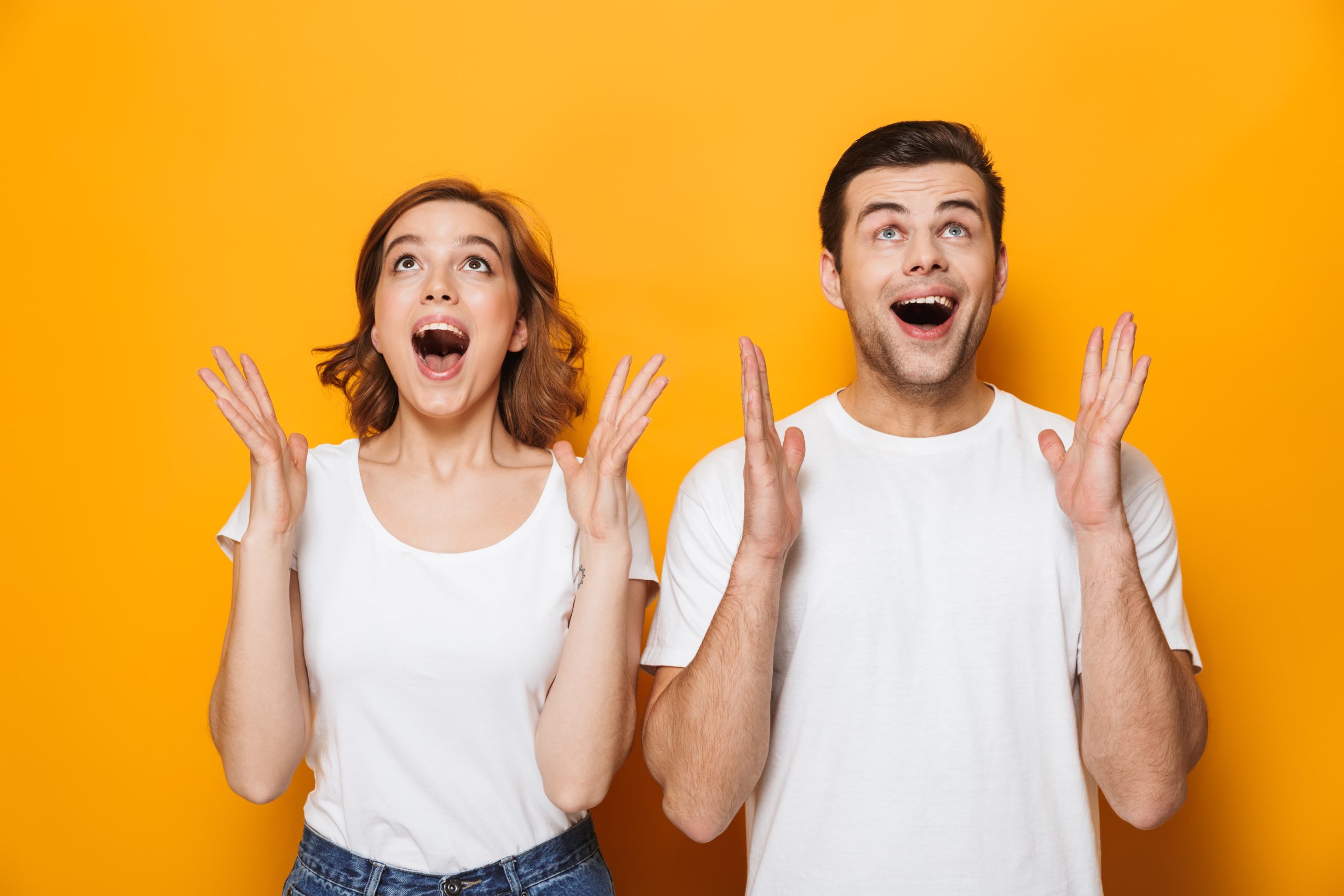 Woman and man in white t-shirts looking surprised