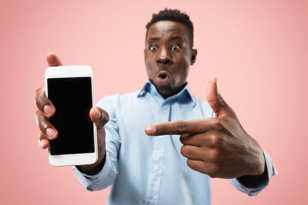 Man holding a smartphone and pointing to it with his left hand