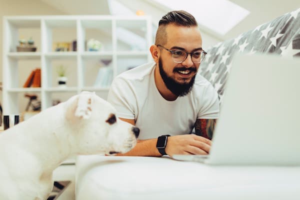 Man on his computer with white dog watching
